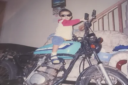 Álvaro quando criança, sentado em uma moto na sala de casa