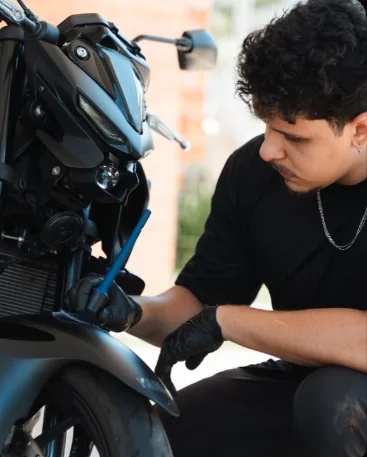 Álvaro detalhando uma moto, atento aos detalhes, vestido de preto