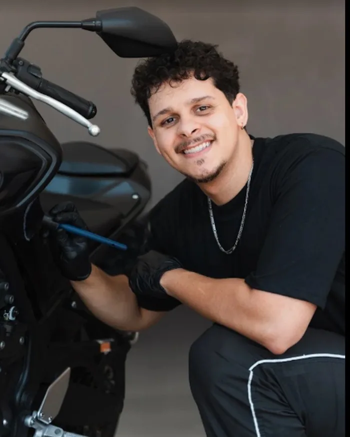 Álvaro sorrindo ao lado de uma moto, na oficina da ZERO